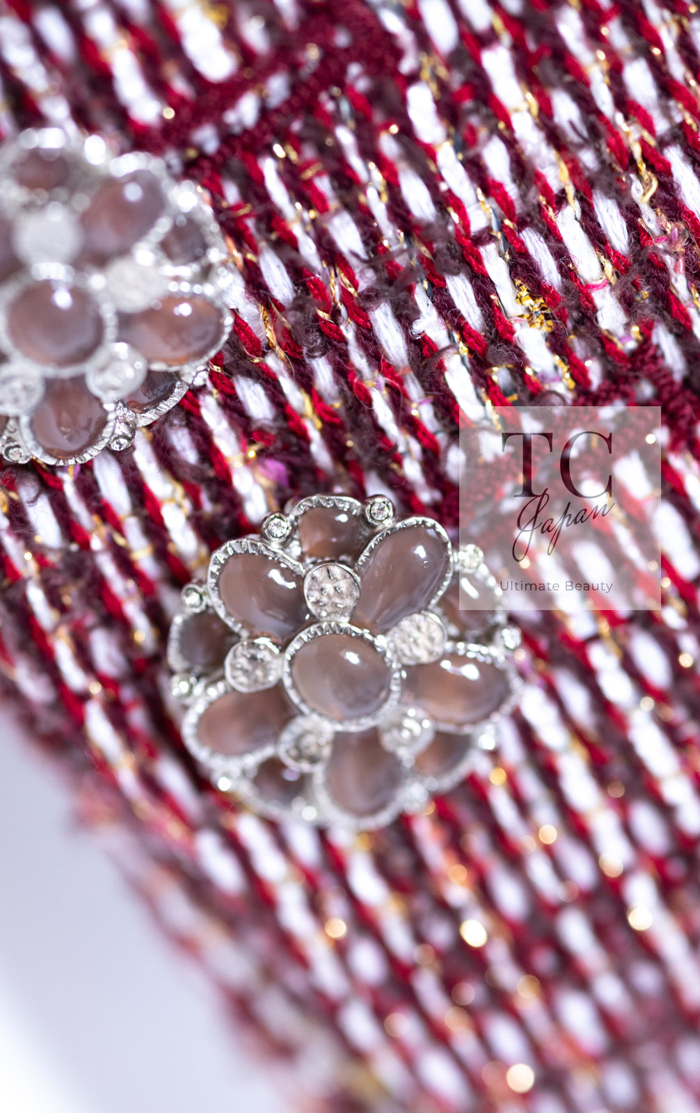 CHANEL flower-shaped jewel buttons on red and white tweed close-up